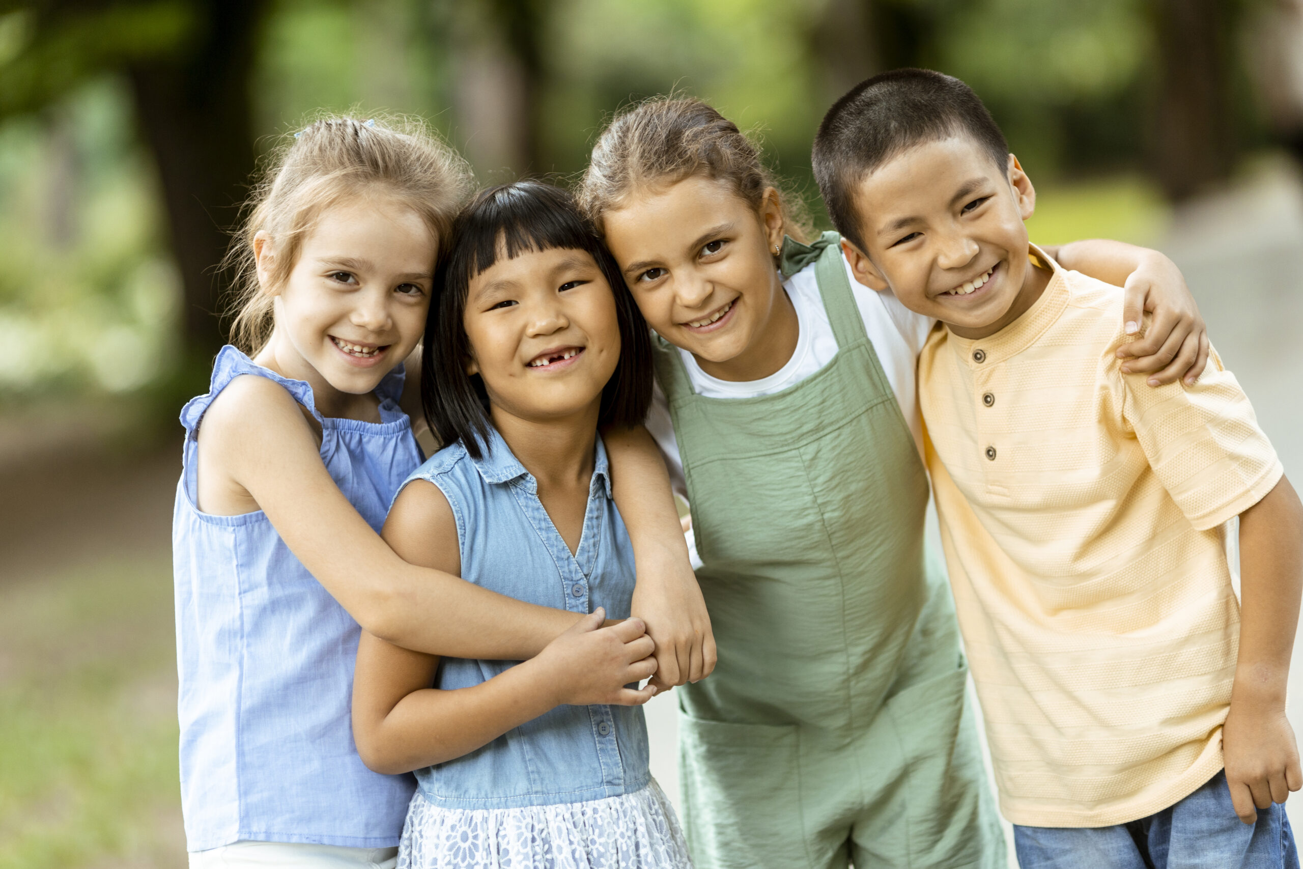 Four diverse children smiling and hugging, showcasing friendship and inclusivity.
