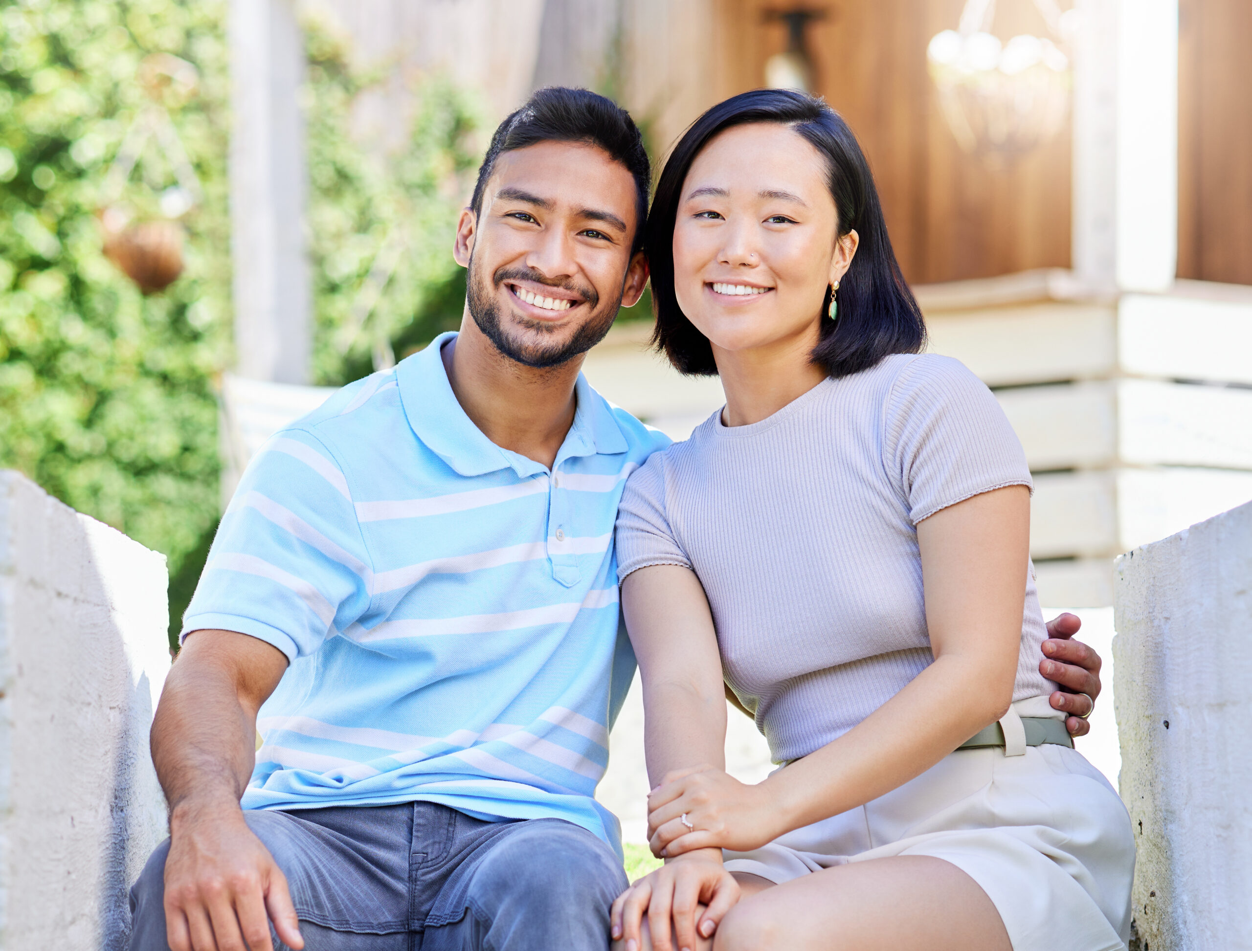 Happy couple sitting together outdoors, smiling at the camera.