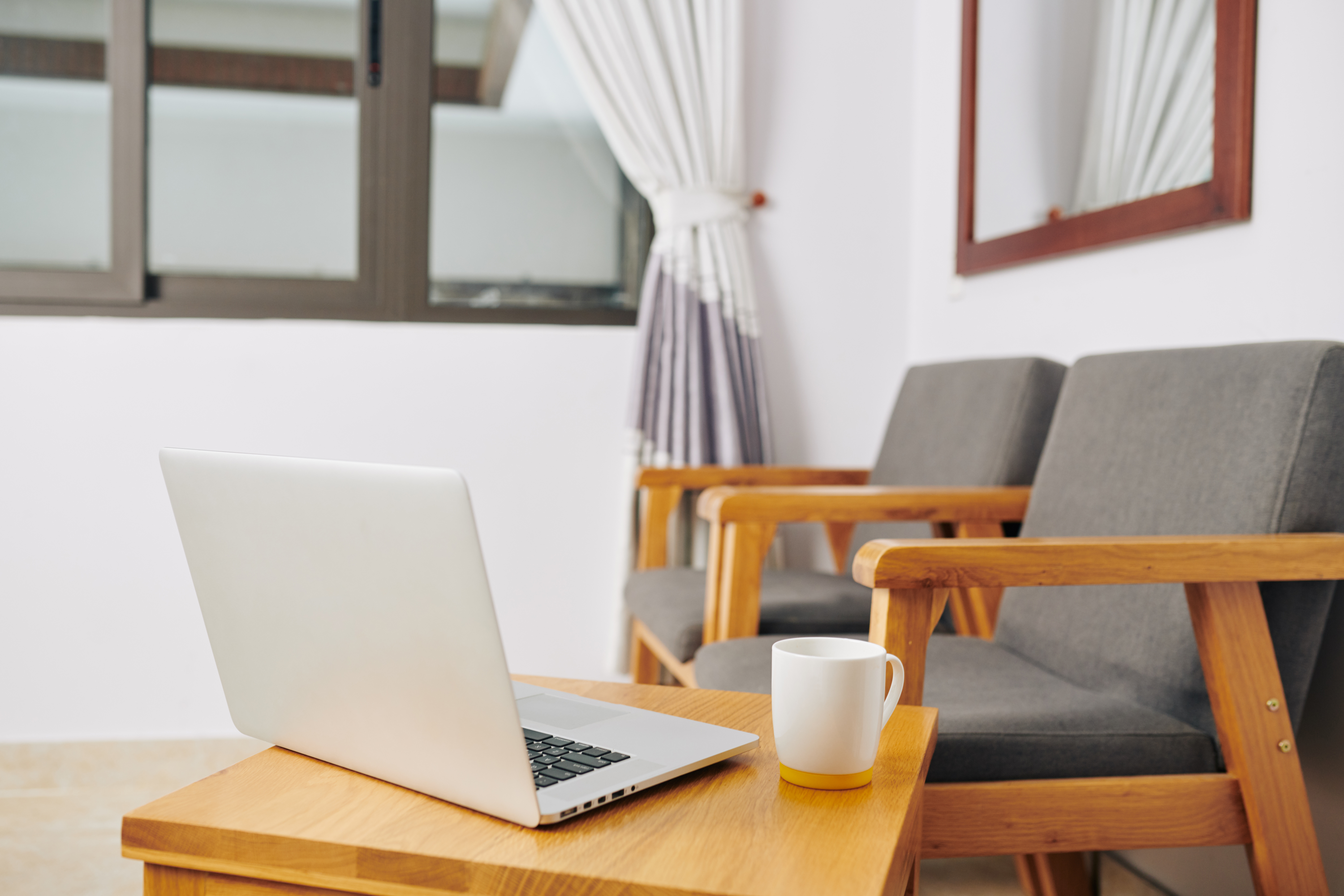 Laptop and coffee mug on a wooden table in a cozy home living room