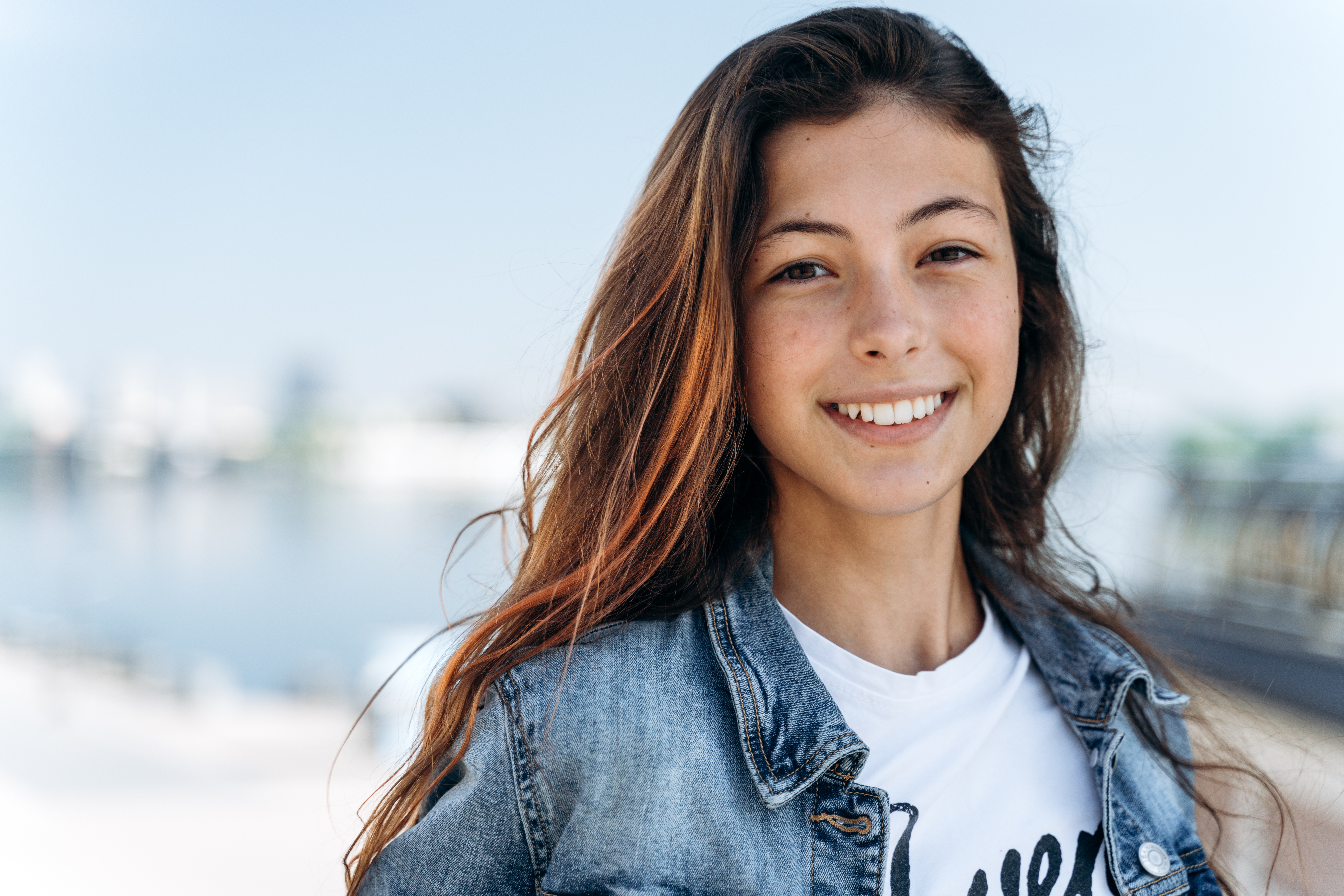 Smiling woman in denim jacket by a waterfront