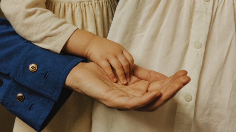 A child's hand resting gently in an adult's open hand