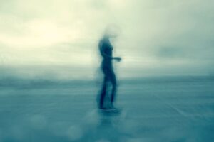 Blurred figure of a woman walking on a beach.
