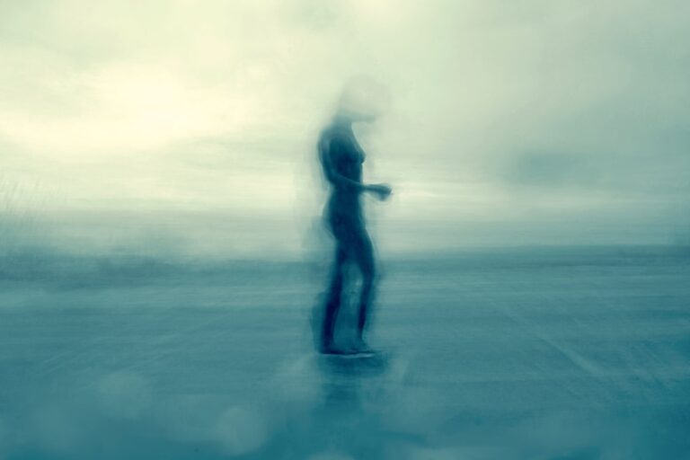 Blurred figure of a woman walking on a beach.