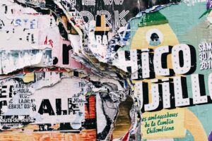 Torn street posters with "Chico Jillo" and other text visible. Layered, textured urban art.