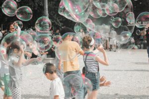 Children playing with giant bubbles outdoors on a sunny day.