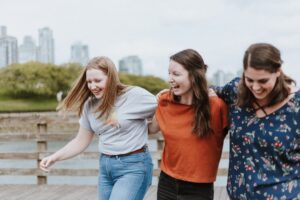 Three happy young women walking together, laughing and enjoying friendship.