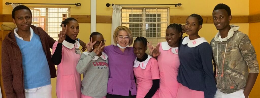 Group photo of medical students and a teacher. Smiling faces and peace signs.