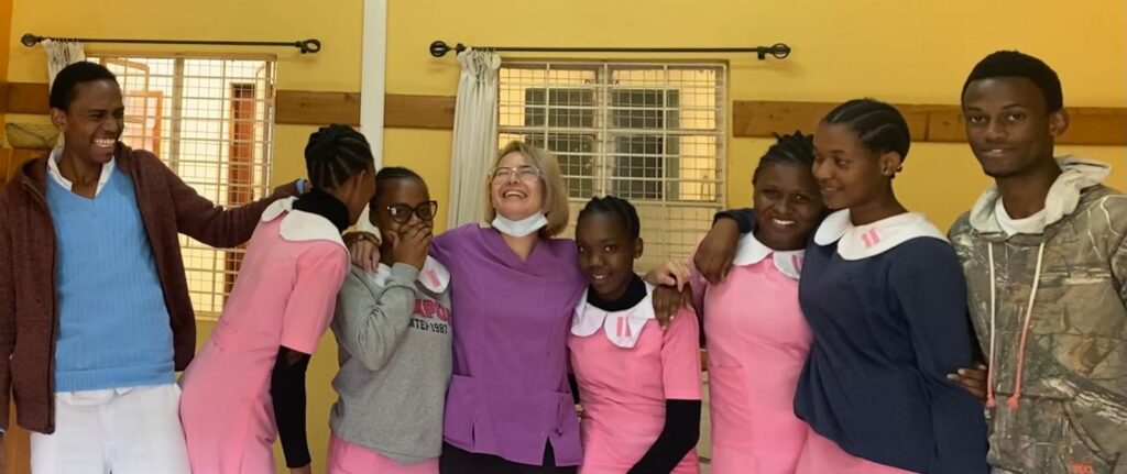 Group smiling in colorful outfits in a bright room.